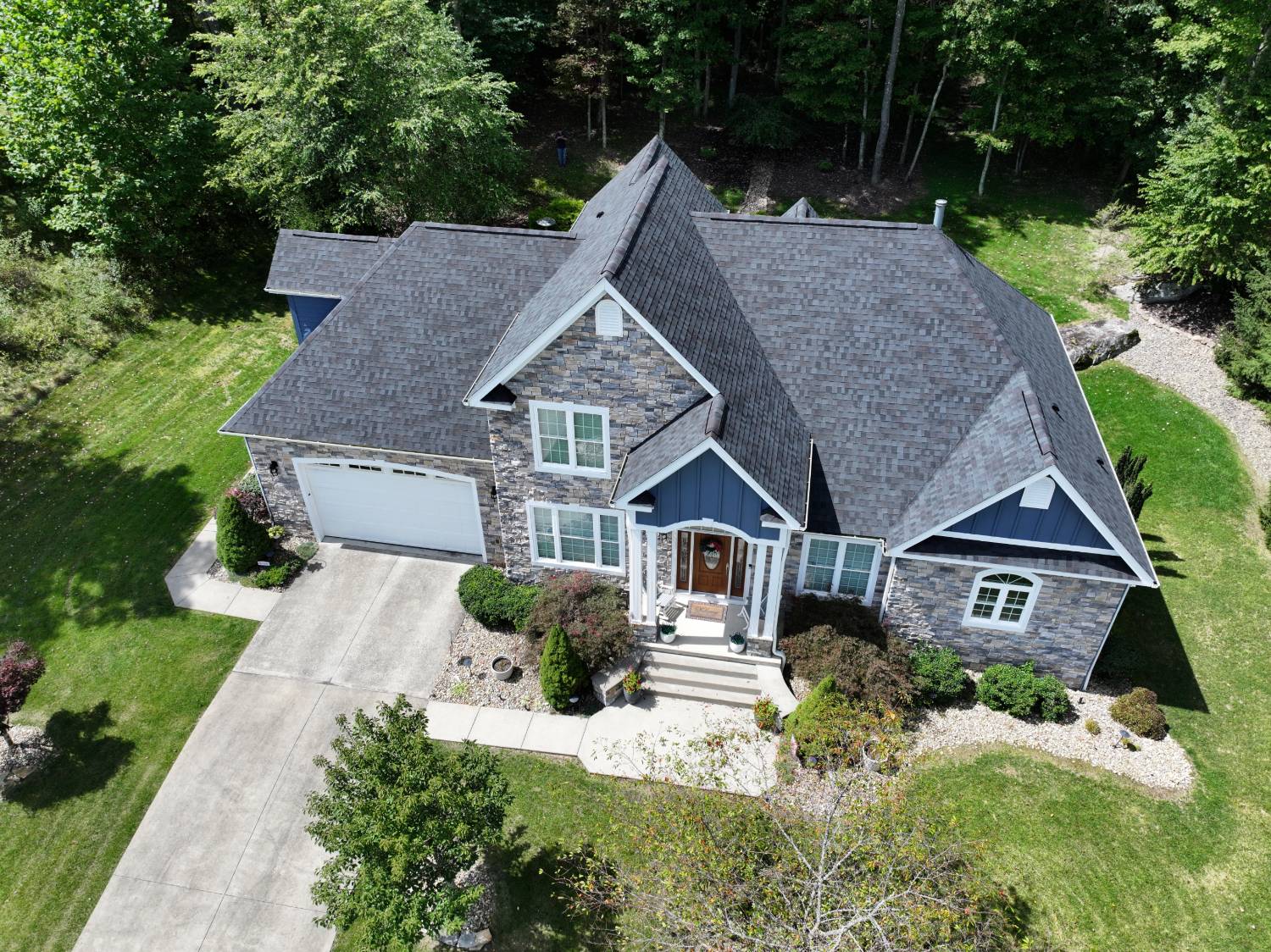 Completed roof replacement by Eclipse Construction on a stone-front Cheat Lake WV home, with new shingles and custom gutters