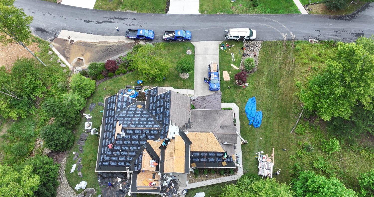 Eclipse Construction crew tearing off an old roof on a Cheat Lake WV home, with new underlayment going down