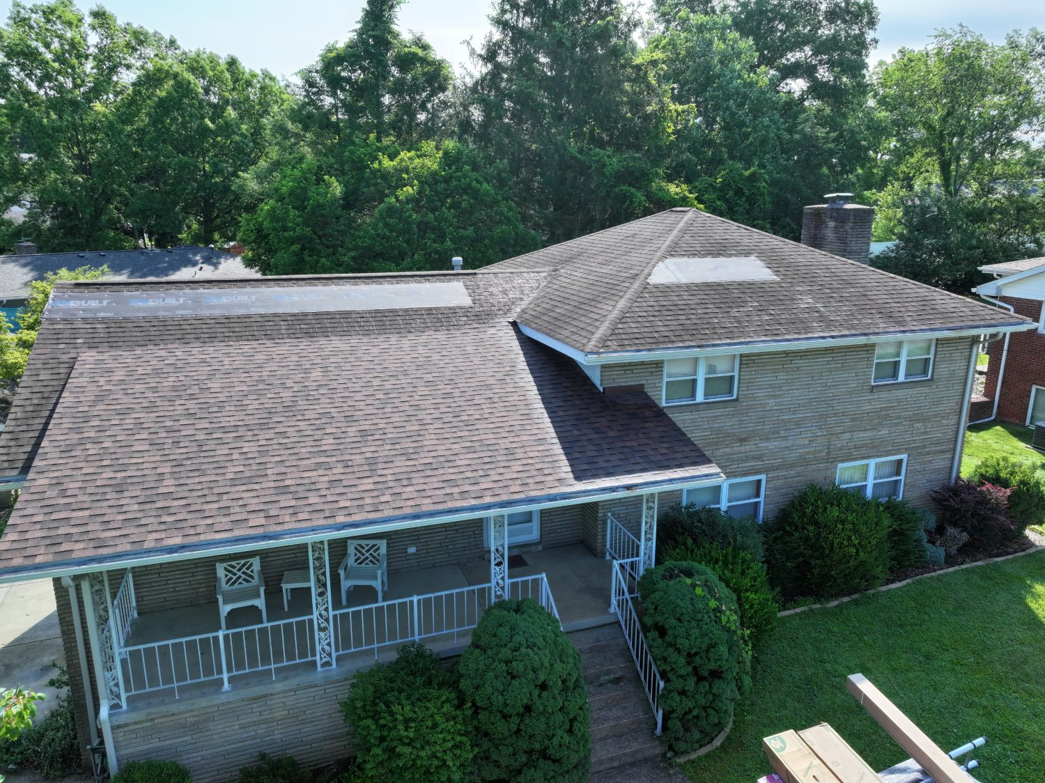 Morgantown WV brick home before roof replacement, showing weathered brown shingles and patched sections